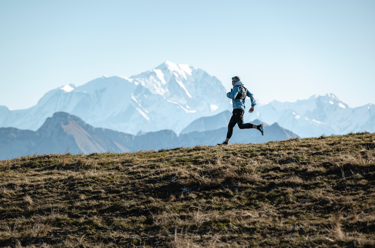 Trail runner moving through an open mountain landscape